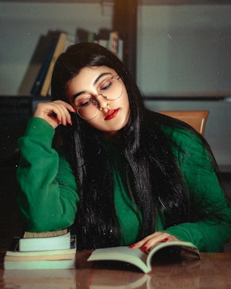 a woman sitting at a table reading a book