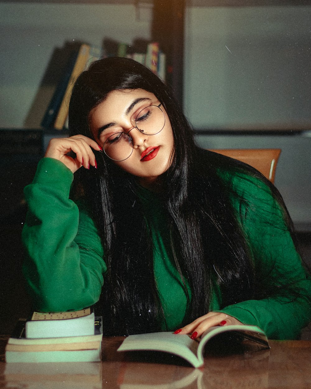 a woman sitting at a table reading a book