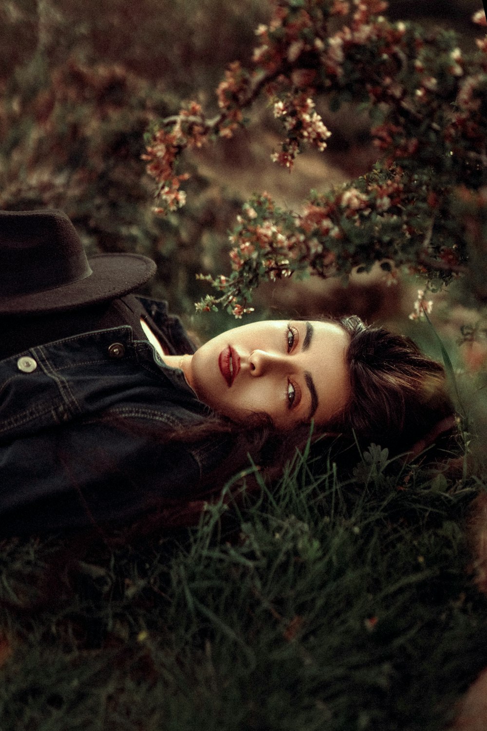 a woman laying in the grass with a hat on her head