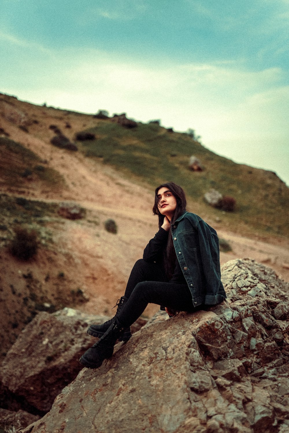 a woman sitting on top of a large rock