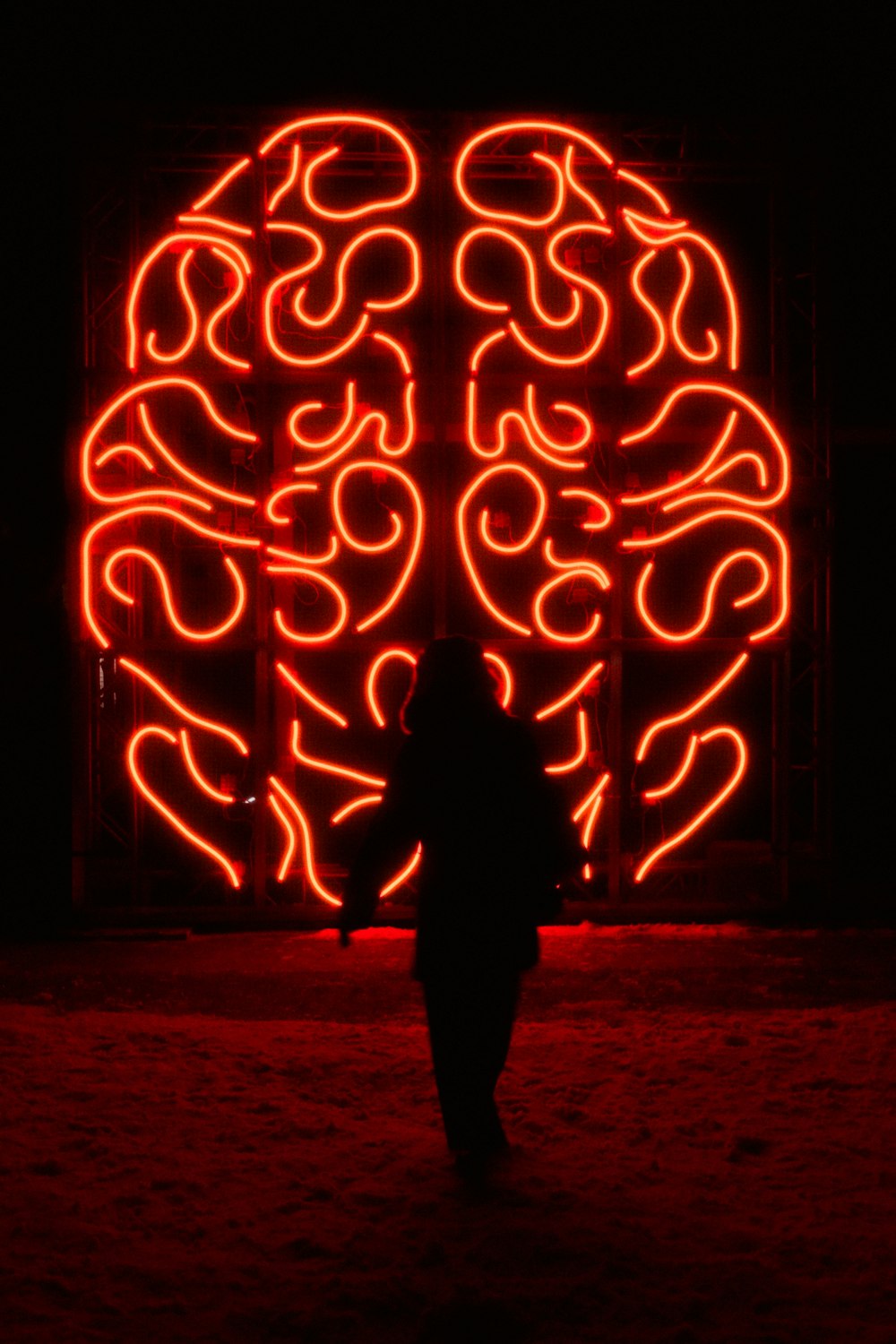 Una persona in piedi di fronte a un grande cervello al neon