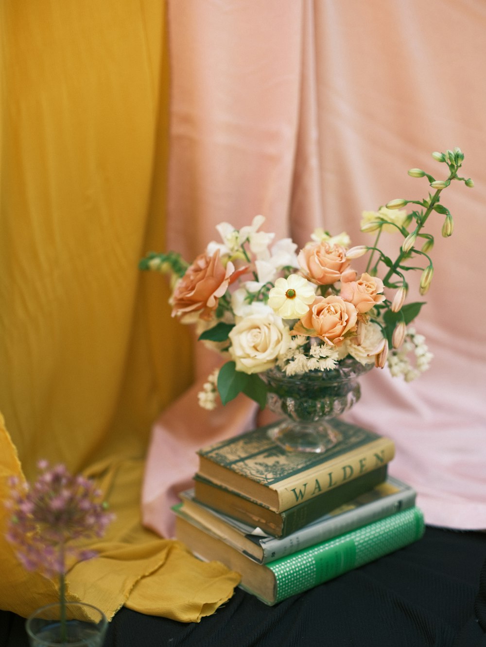 um vaso de flores sentado em cima de uma pilha de livros