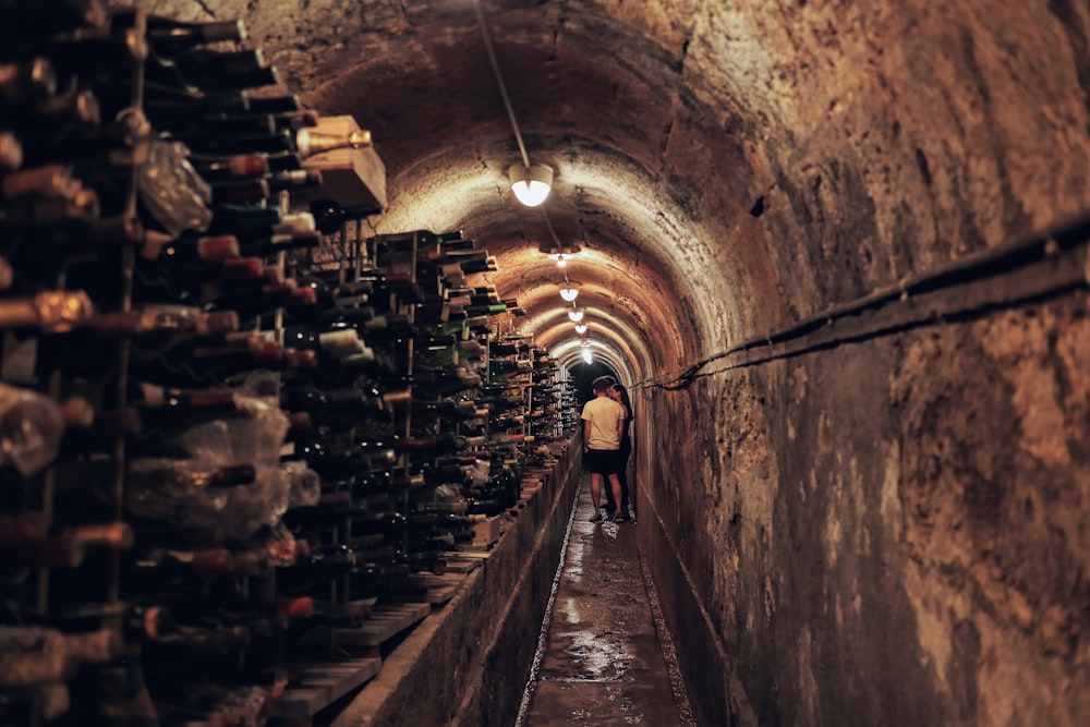 Un hombre caminando por un túnel lleno de muchas botellas