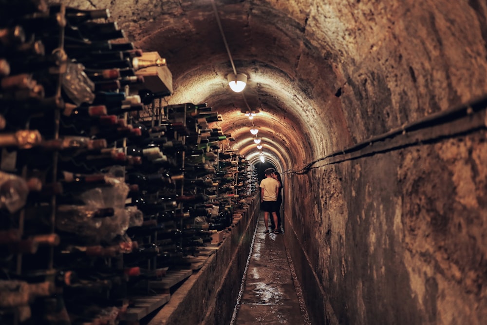 a man walking down a tunnel filled with lots of bottles