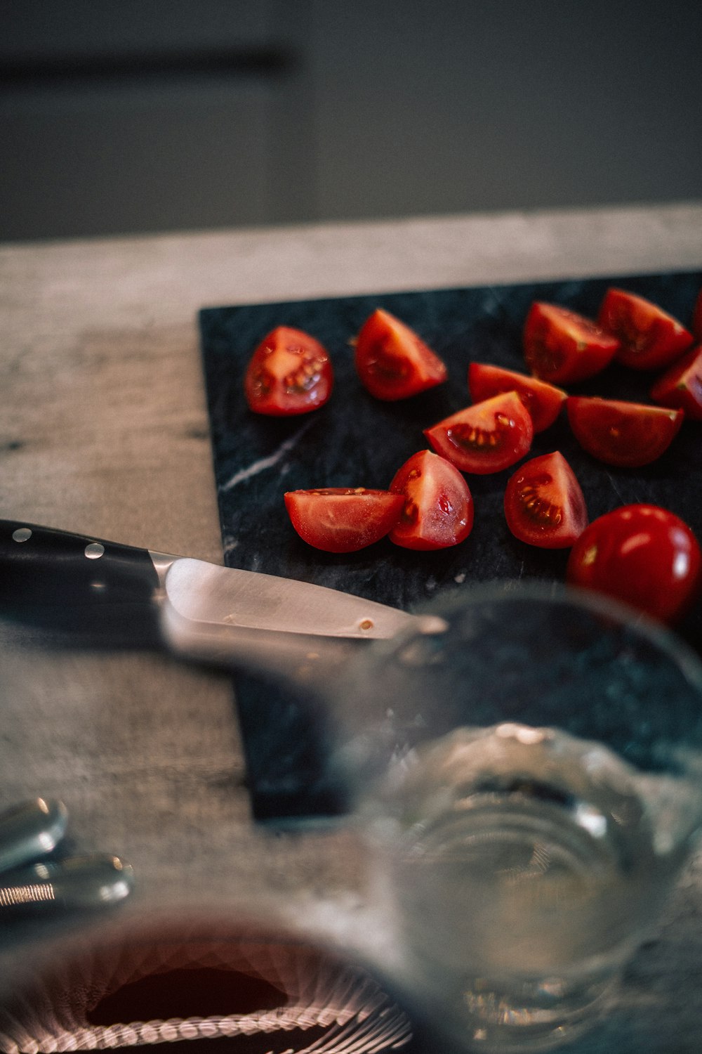 una tabla de cortar cubierta con tomates en rodajas junto a un cuchillo