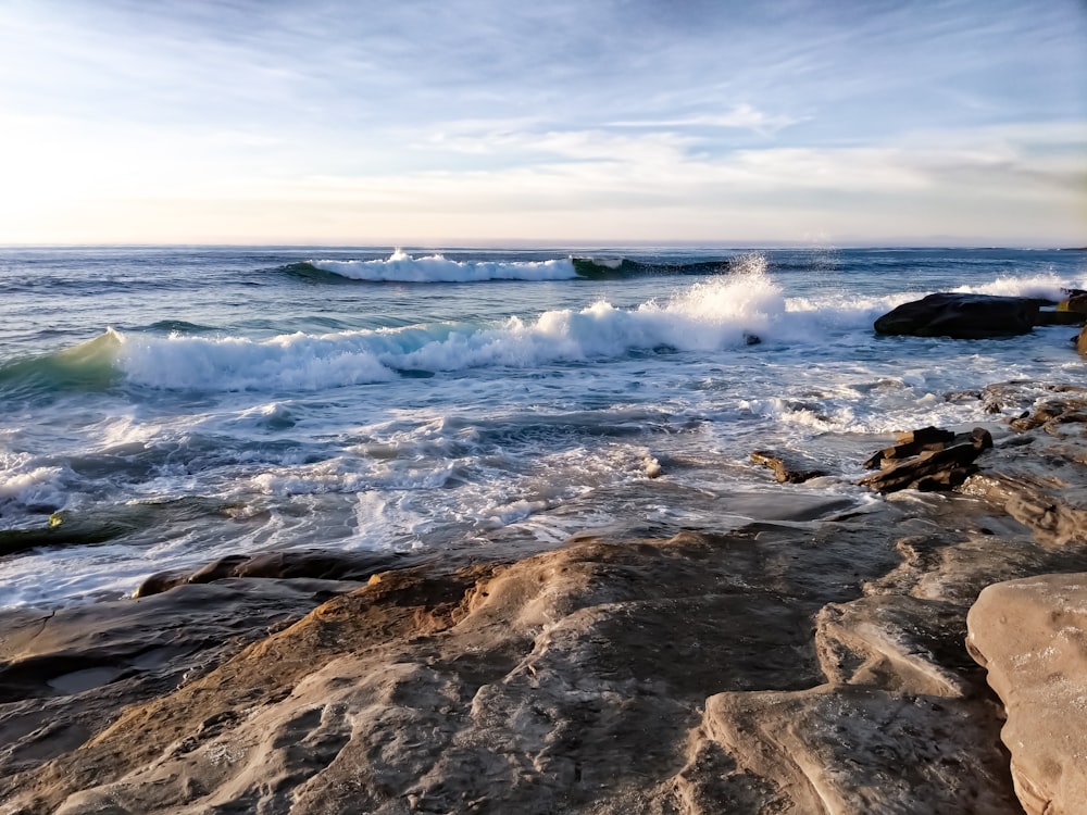 a rocky beach with waves crashing on the rocks