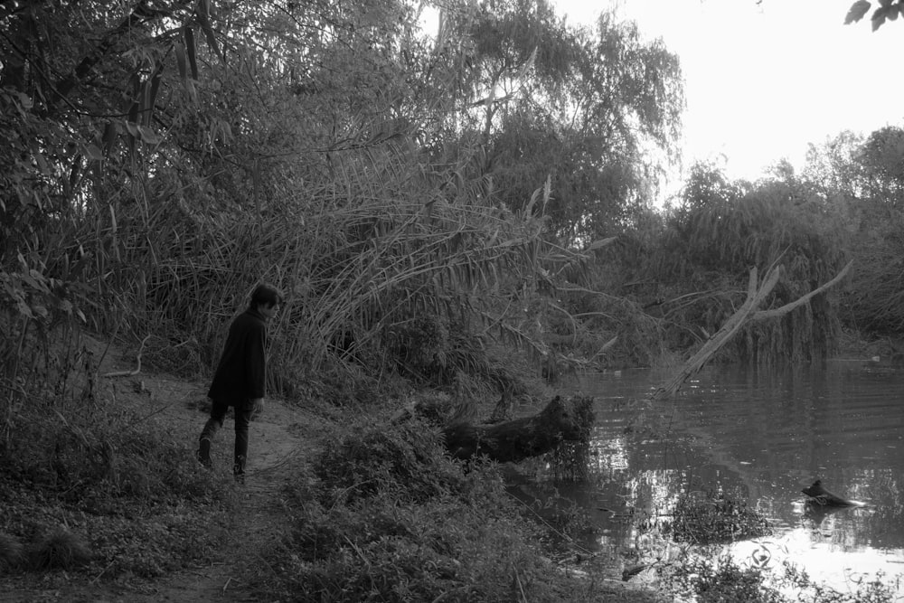 a black and white photo of a person walking near a body of water