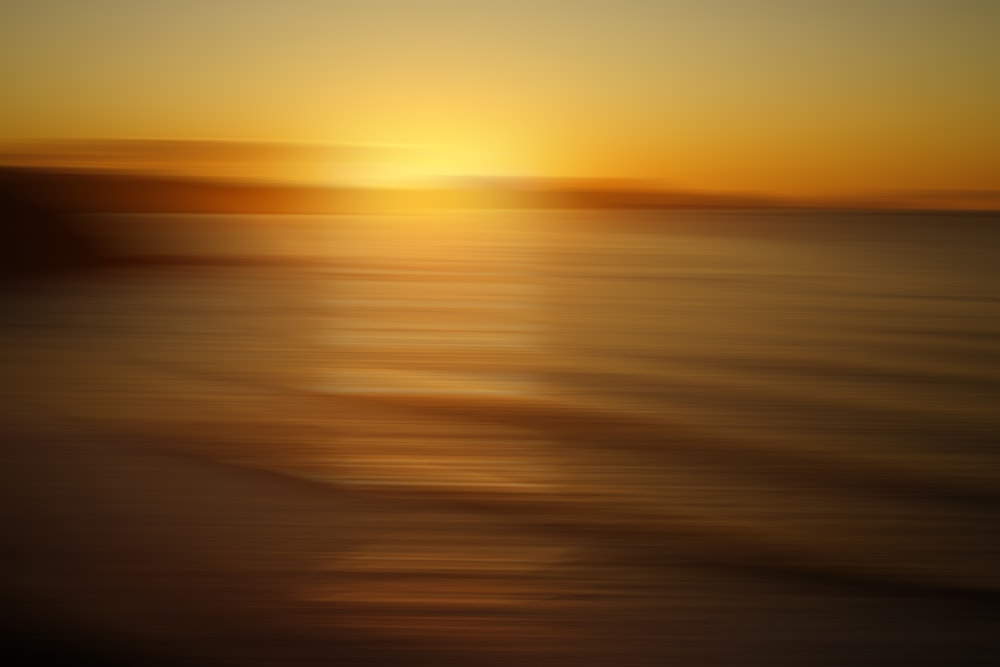 a blurry photo of the sun setting over the ocean