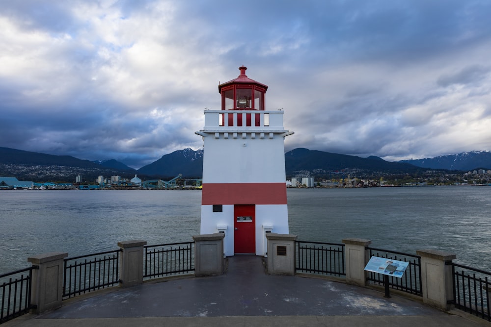 a red and white lighthouse sitting on top of a pier