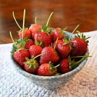 Strawberry pulp with visible seeds in a rustic ceramic bowl on a wooden surface.