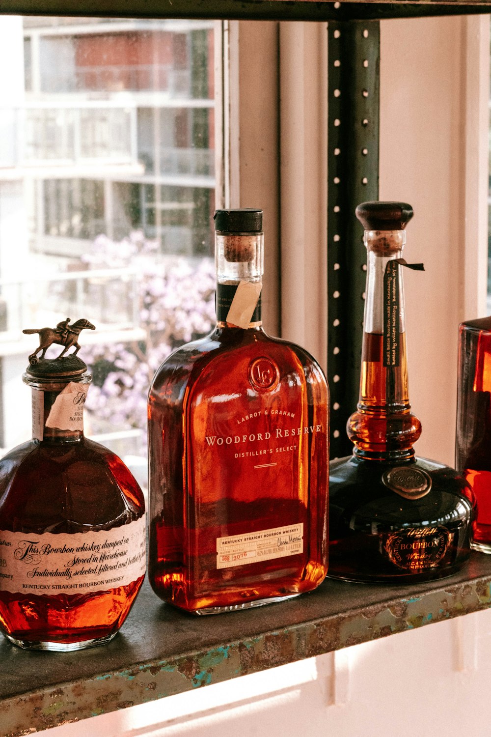 bottles of liquor sit on a shelf in front of a window