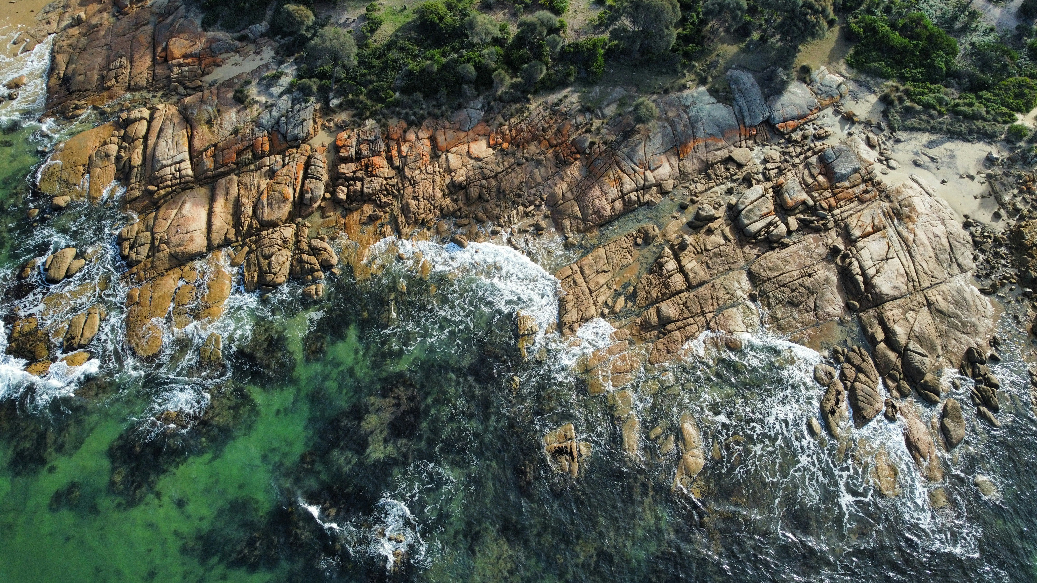 an aerial view of a rocky coastline with green water