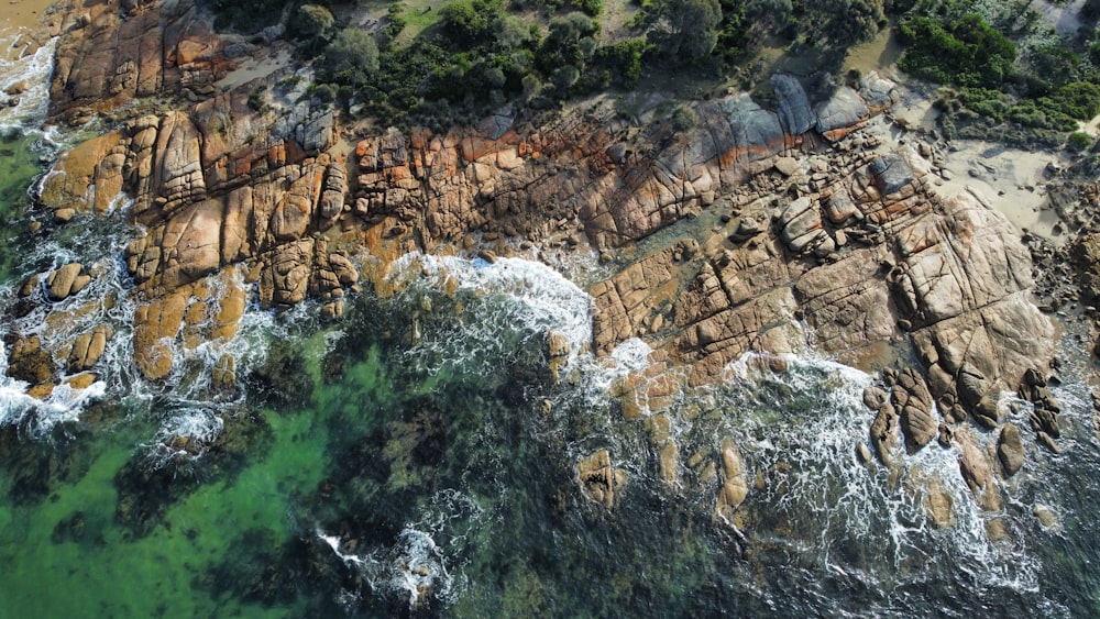 an aerial view of a rocky coastline with green water
