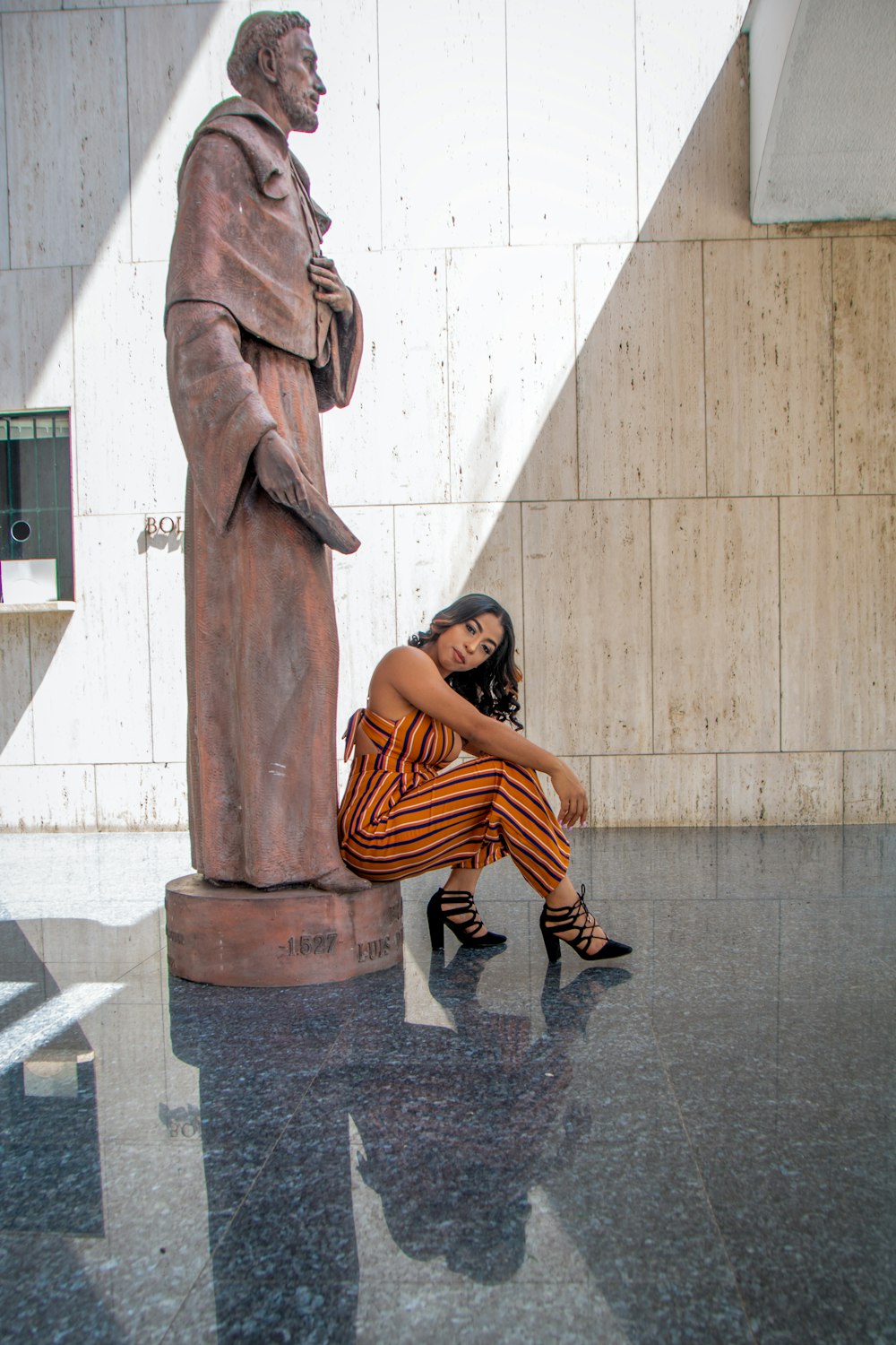 a woman sitting on the ground next to a statue