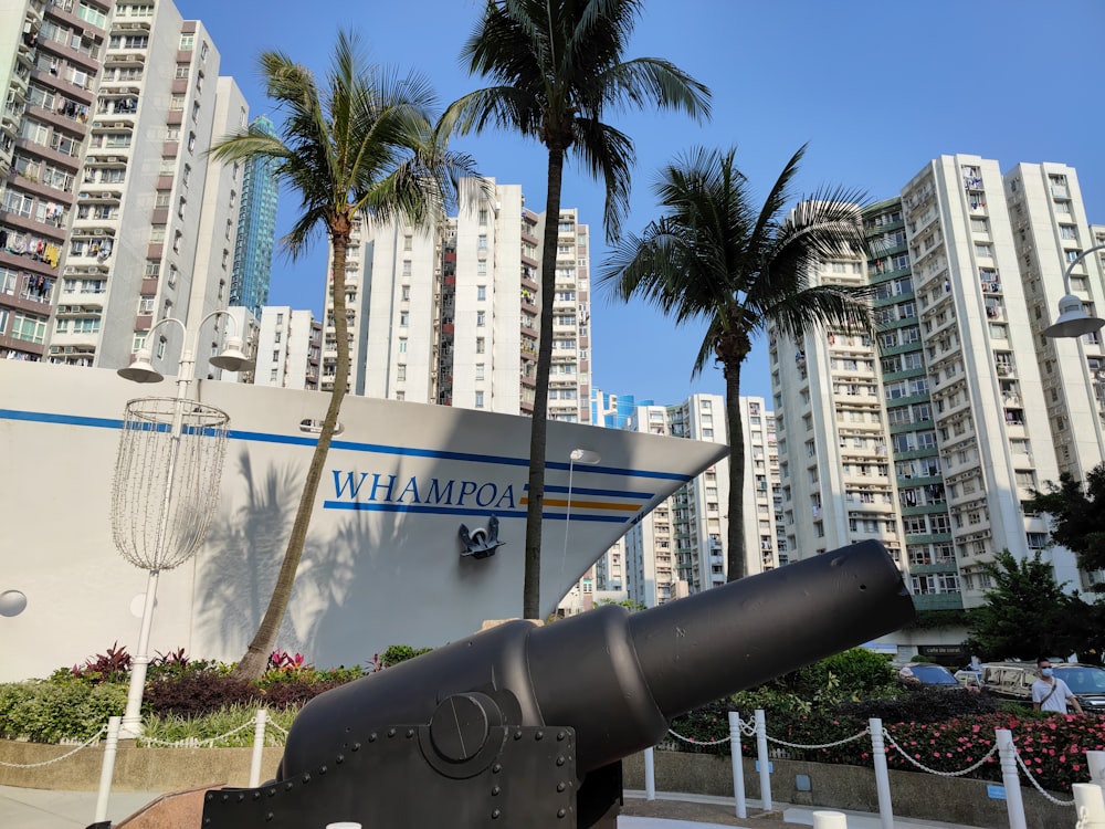 a large metal cannon sitting in front of tall buildings