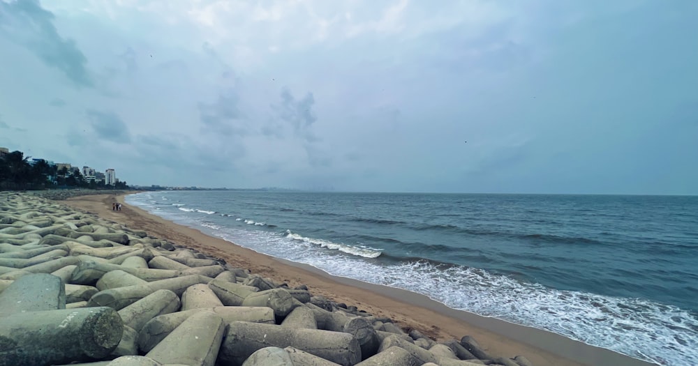 a sandy beach next to the ocean under a cloudy sky