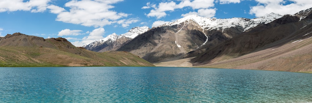 a lake surrounded by mountains under a blue sky