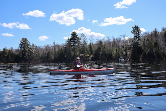 Person kayaking on a calm lake surrounded by trees.