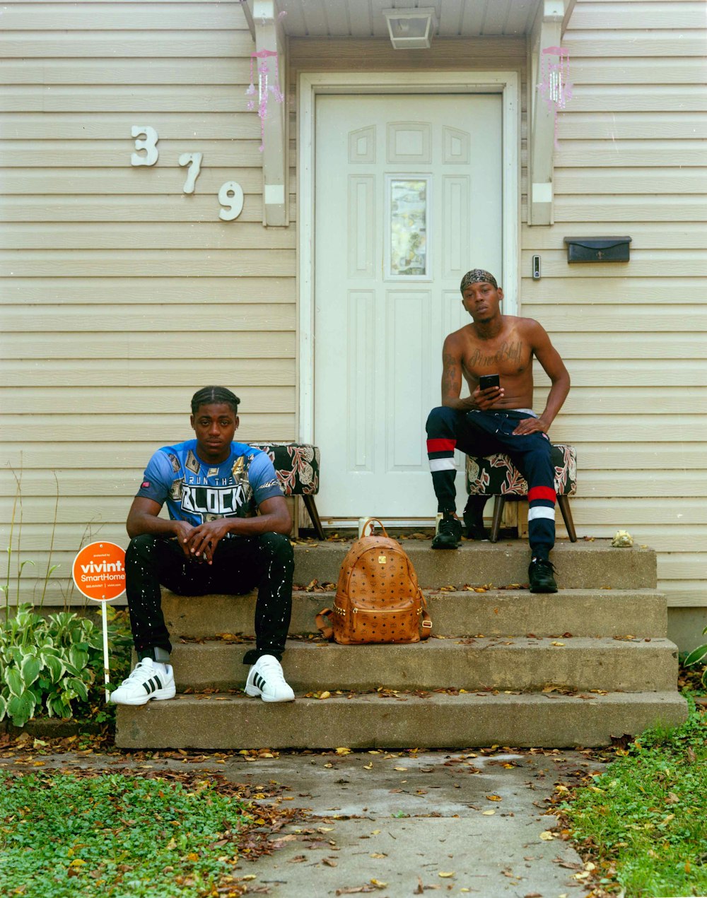 two men sitting on the steps of a house