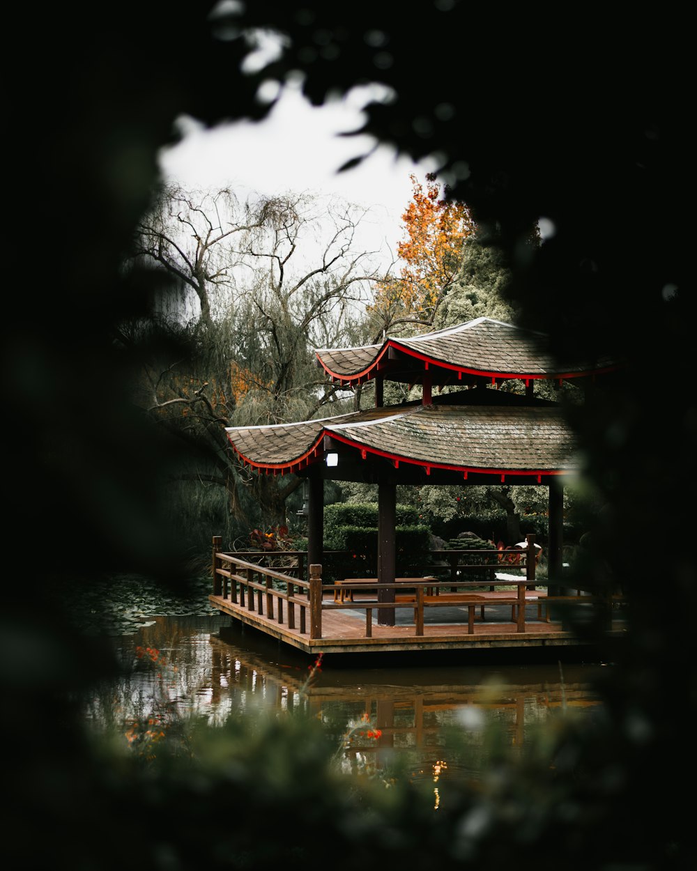 a gazebo sitting on top of a lake next to a forest