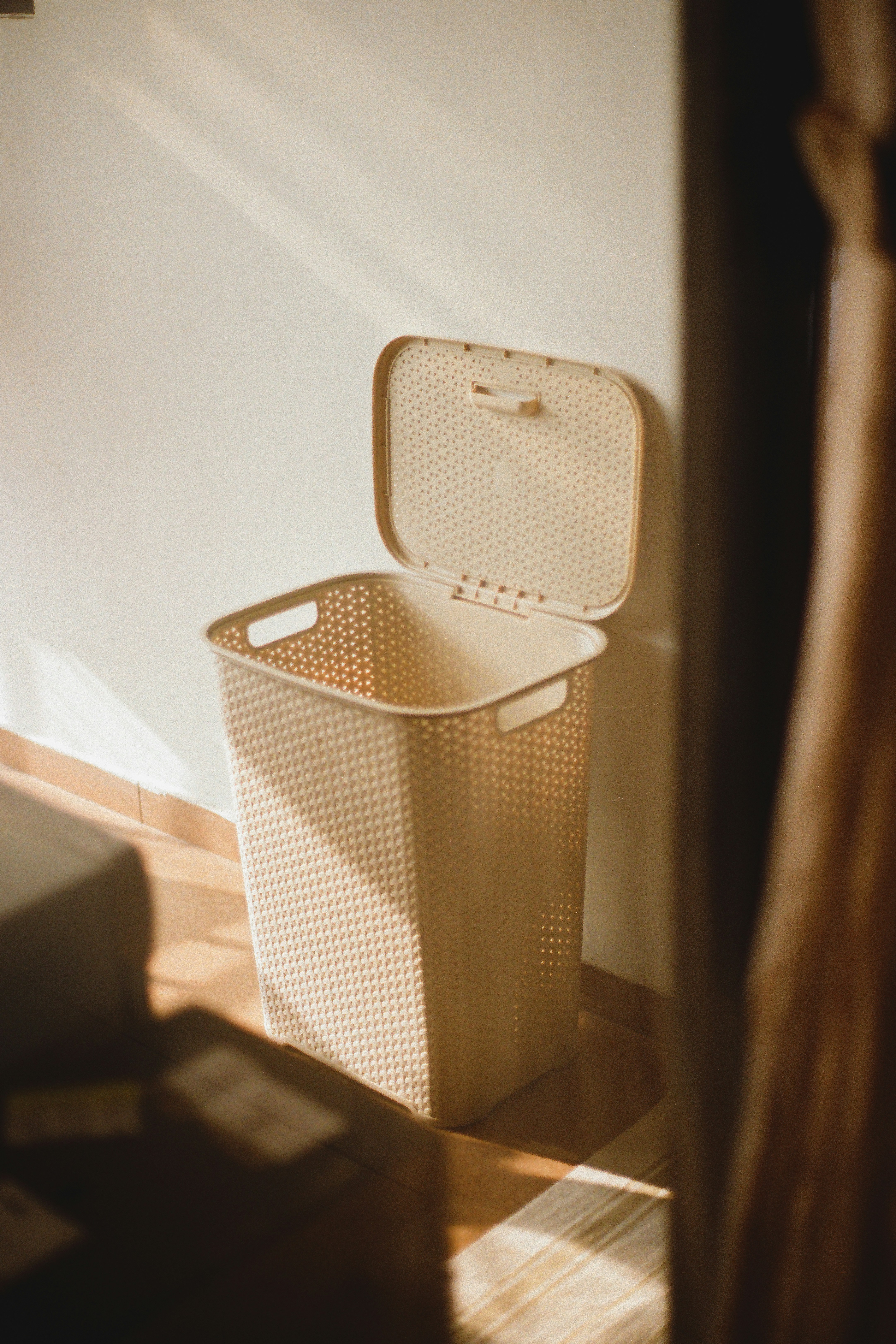 ein weißer Mülleimer neben einer weißen Wand