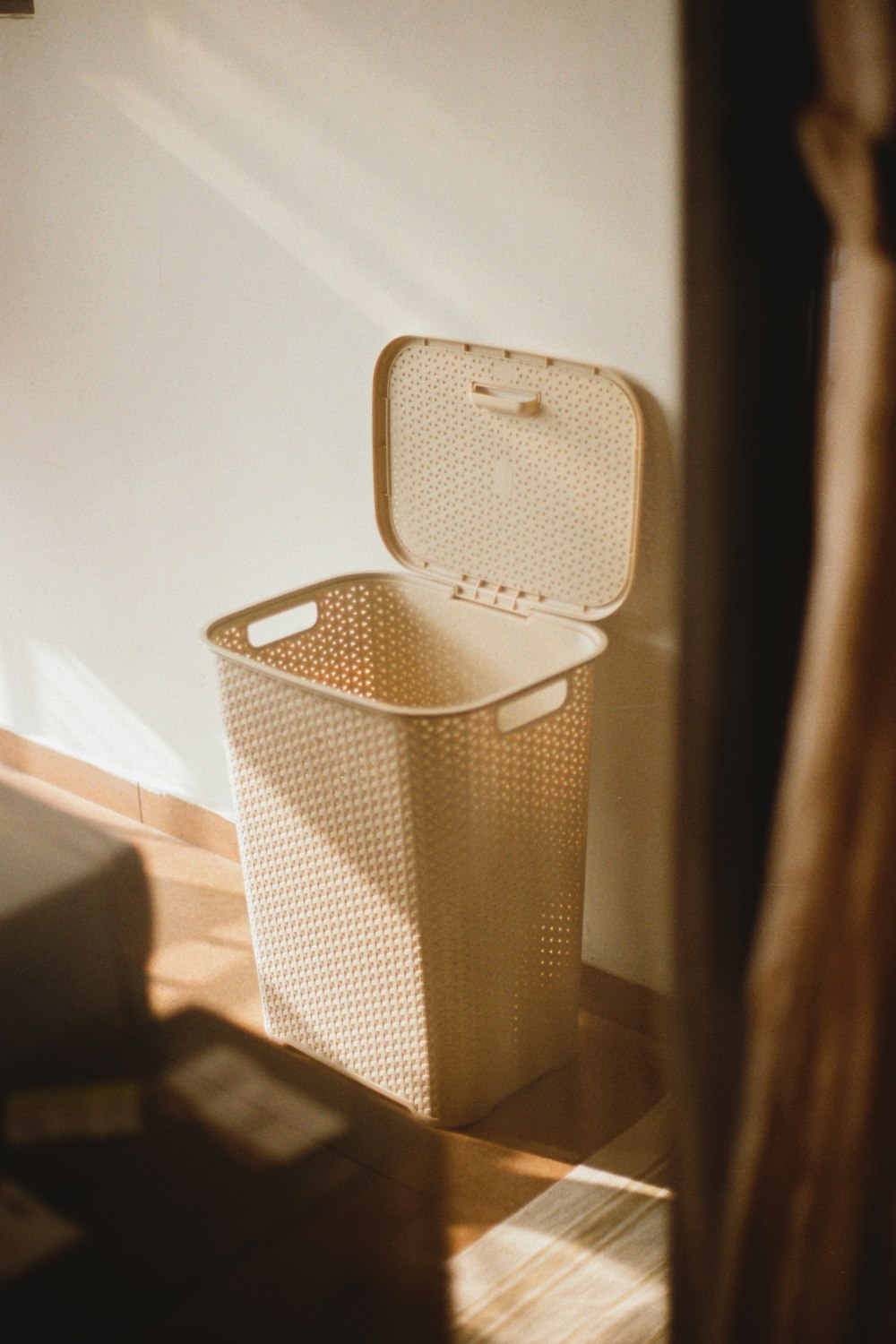 a white trash can sitting next to a white wall