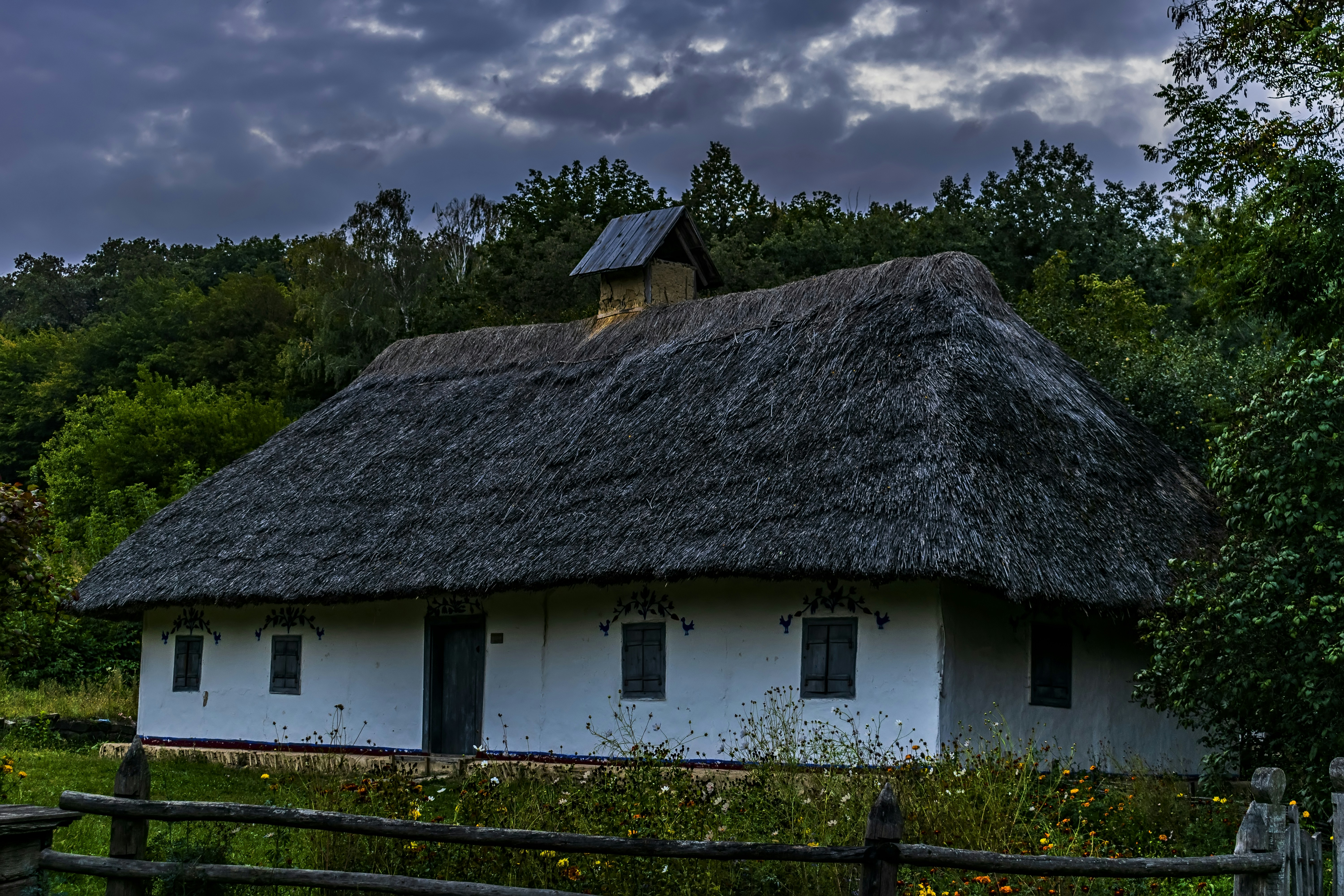 a white house with a thatched roof and a wooden fence in Kazimierz