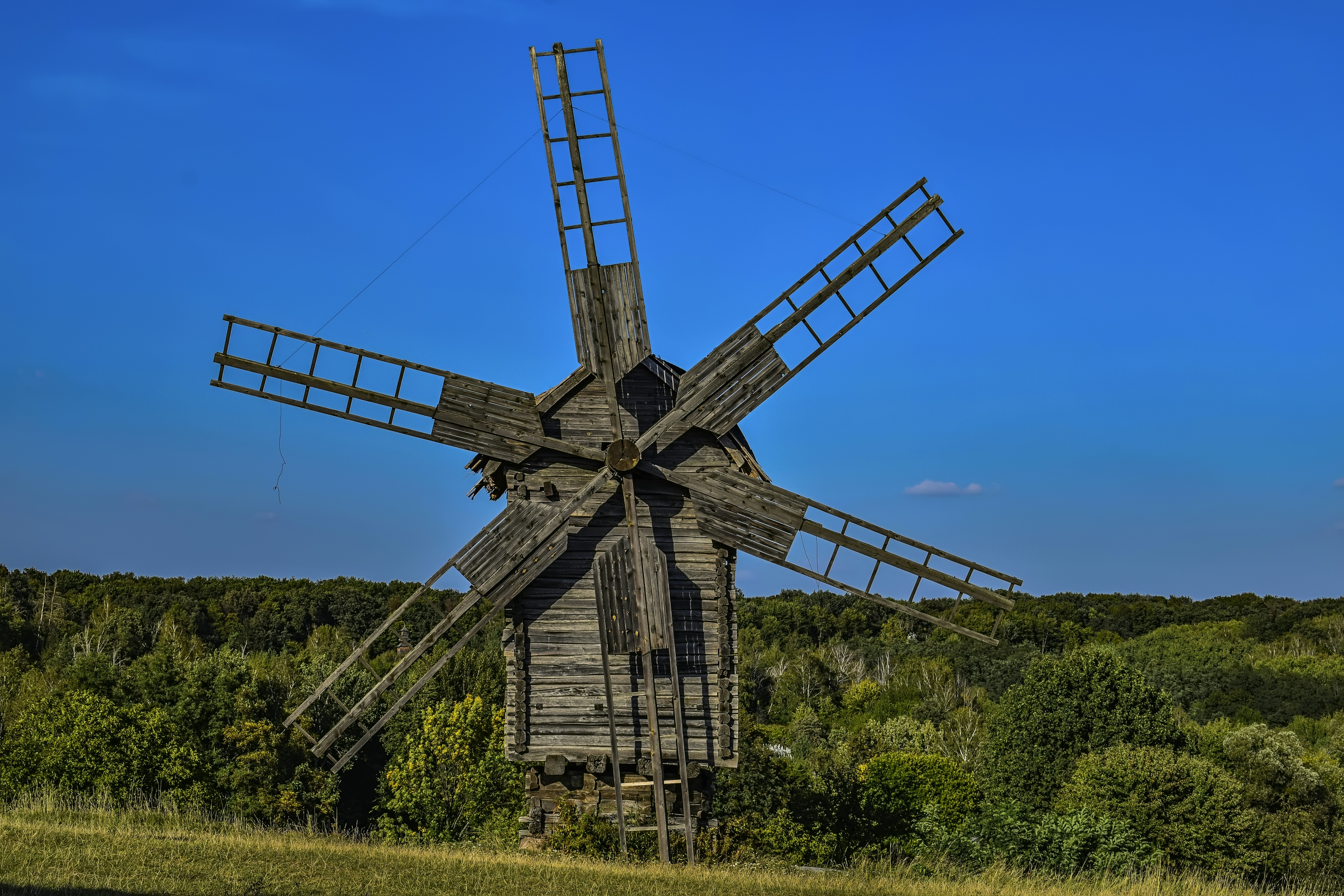 an old wooden windmill in a grassy field