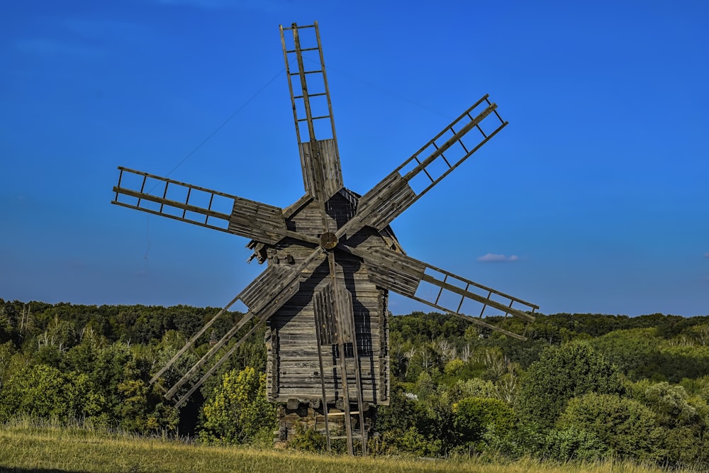 eine alte hölzerne Windmühle auf einem grasbewachsenen Feld