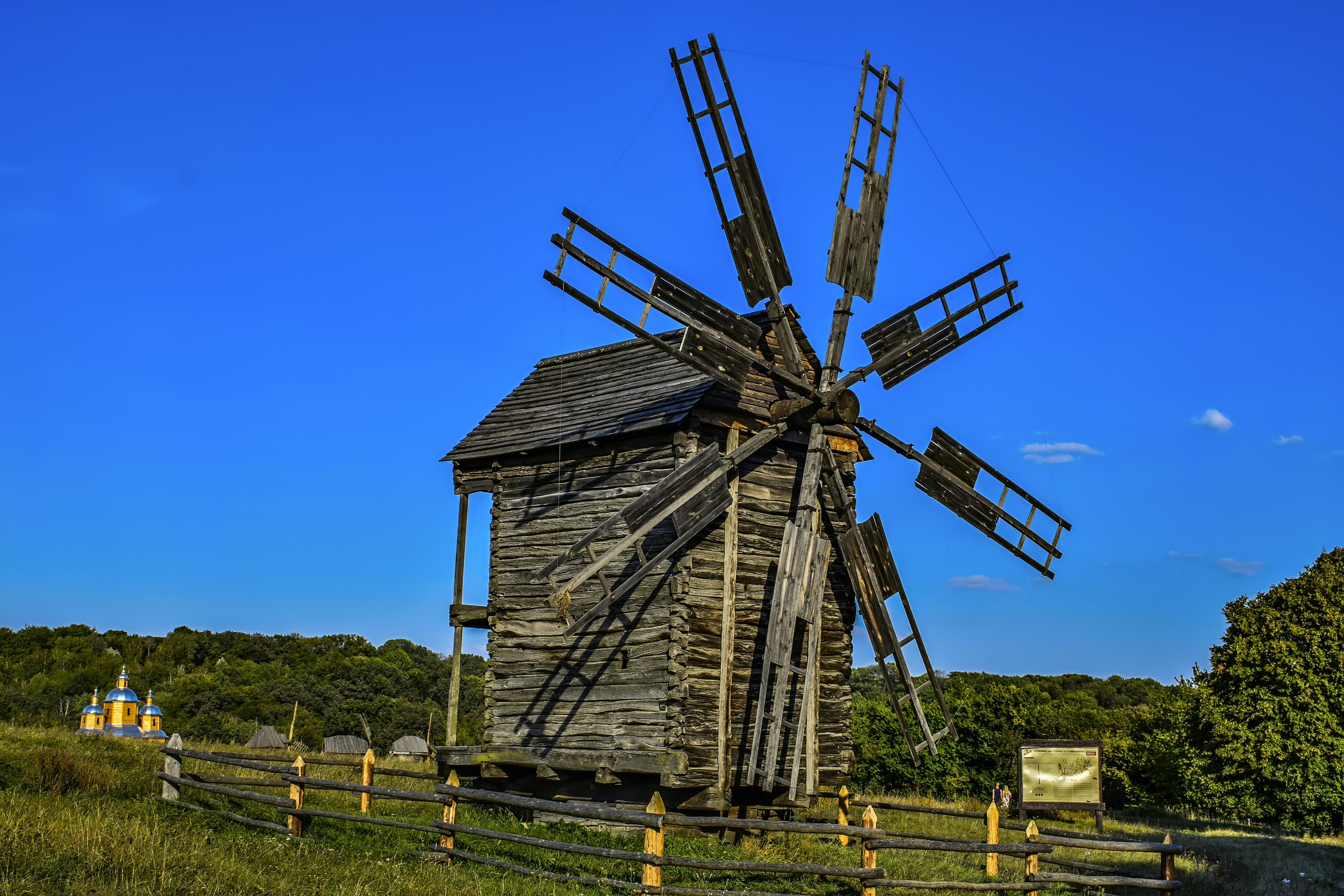 an old wooden windmill sitting on top of a lush green field