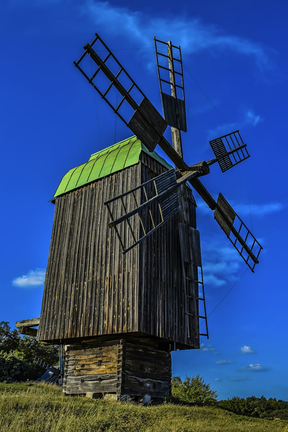 eine alte hölzerne Windmühle mit begrüntem Dach