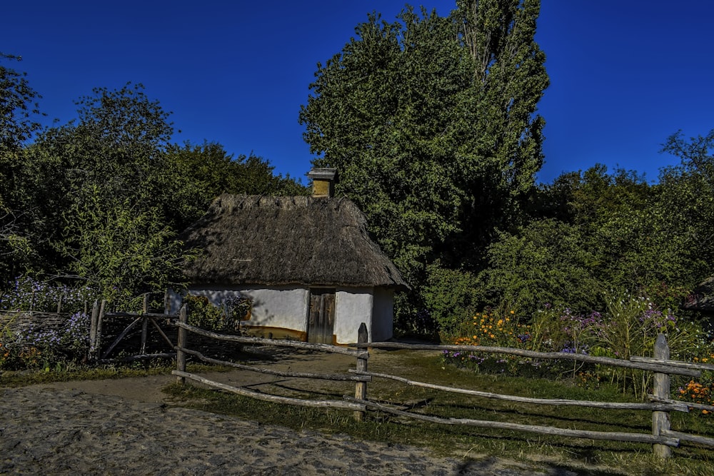 a thatched roof house with a wooden fence around it