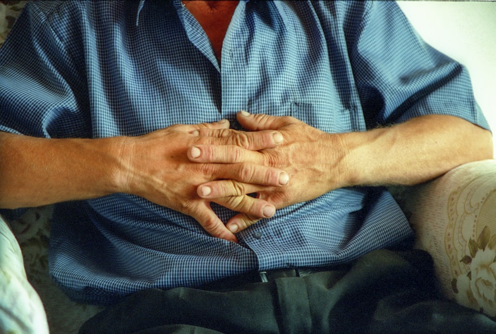 a man sitting on a couch holding his hands together
