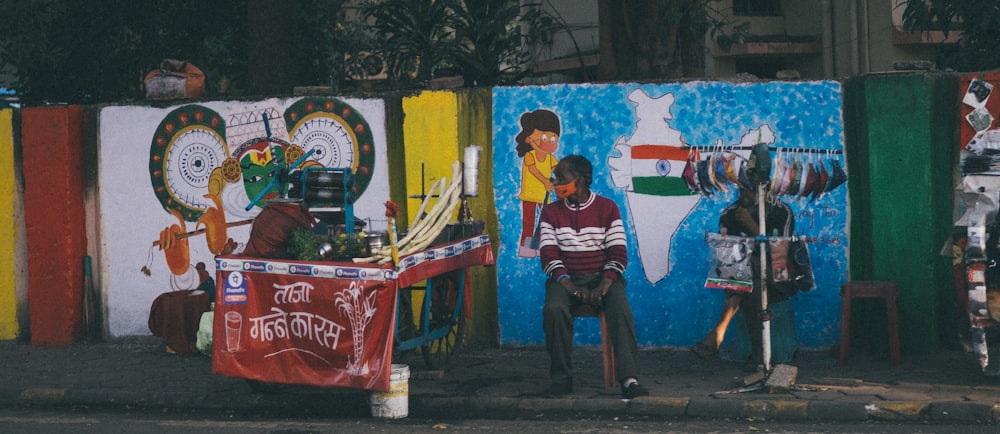 a man sitting on a bench in front of a colorful wall