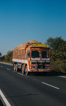 a colorful truck driving down a road next to a forest