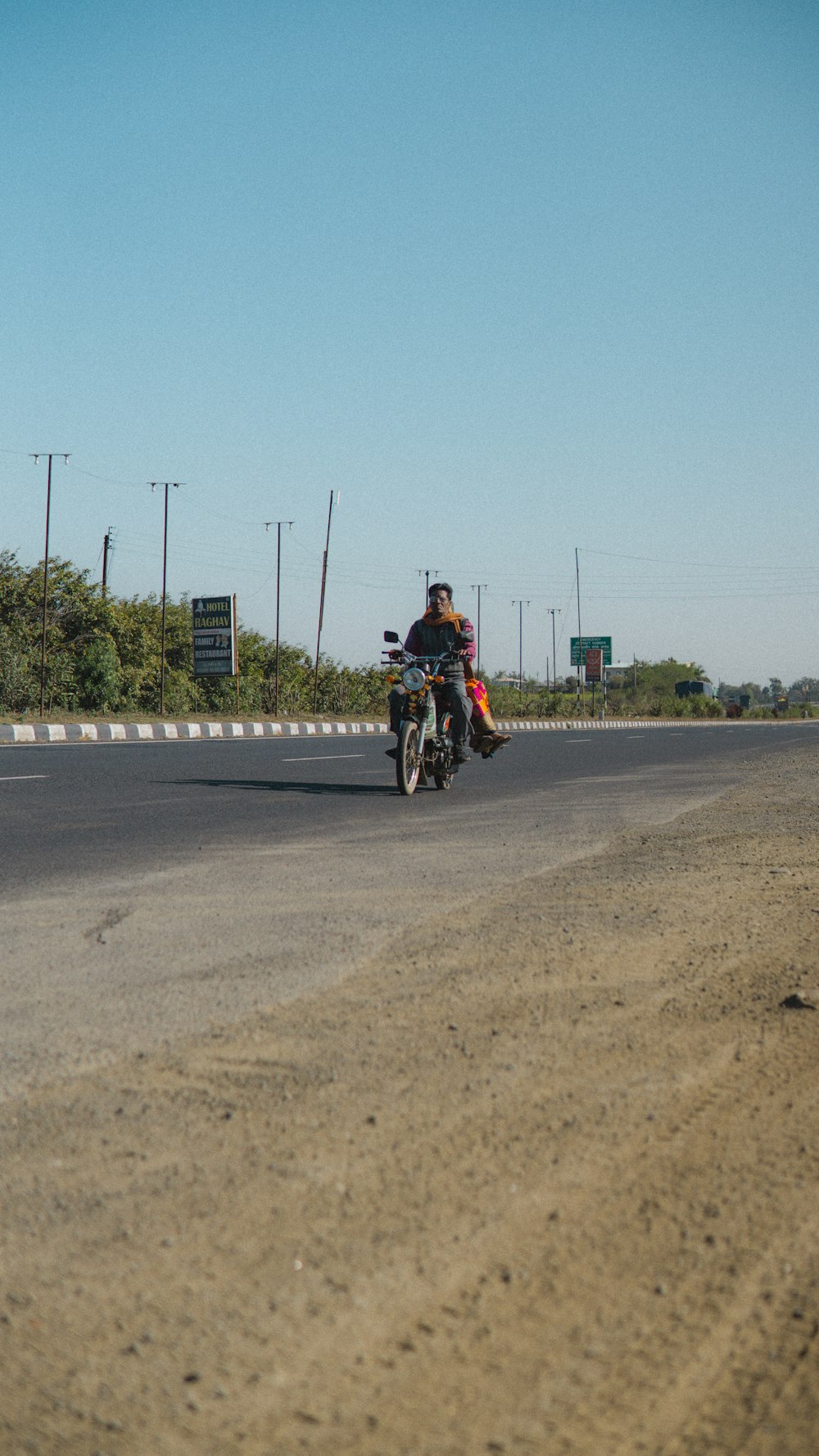 a man riding a motorcycle down the middle of a road