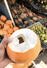A smiling delivery person handing over a crate of coconuts to a local retailer.