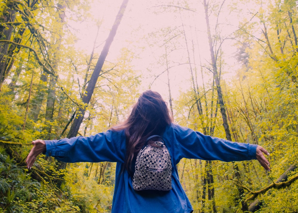 a woman with her arms outstretched in the woods