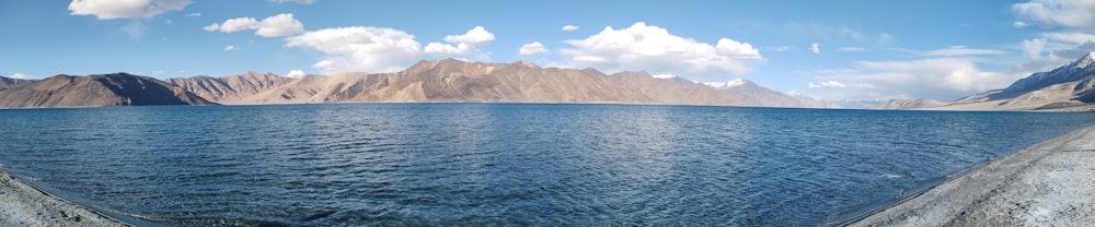 a panoramic view of a lake with mountains in the background