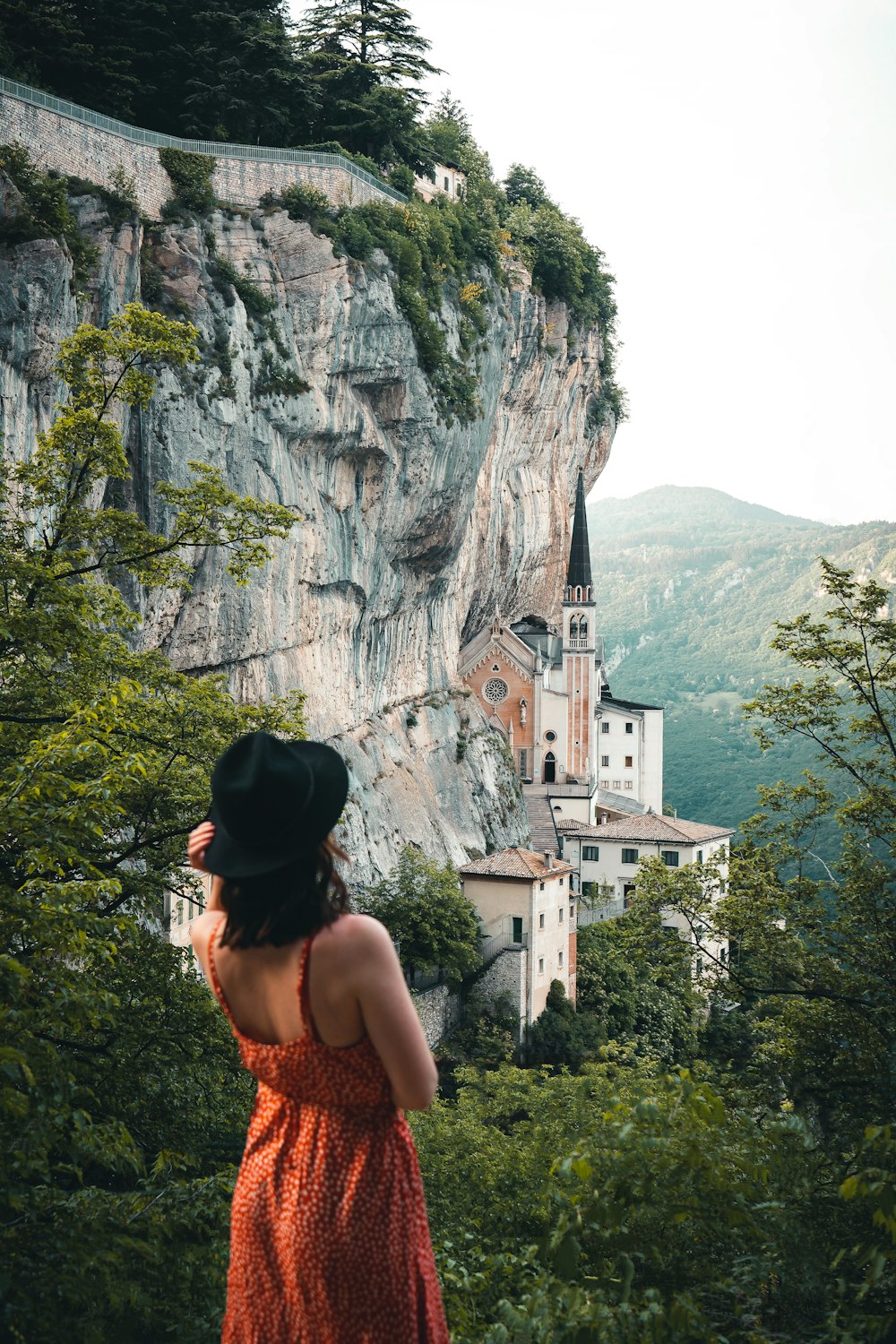a woman in an orange dress looking at a mountain village