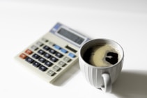 a cup of coffee next to a calculator