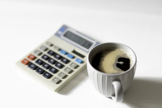 a cup of coffee next to a calculator