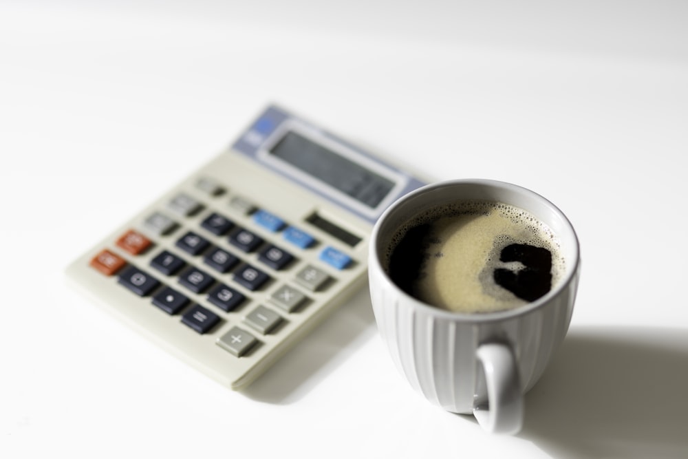 a cup of coffee next to a calculator