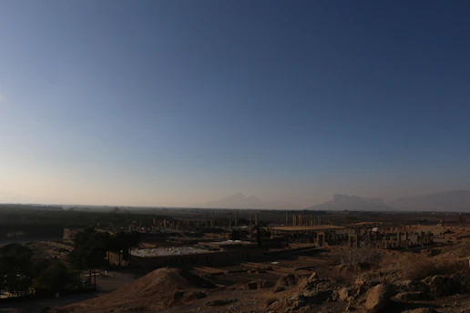 A vibrant fantasy landscape with a hero exploring an ancient ruin under a glowing sunset.