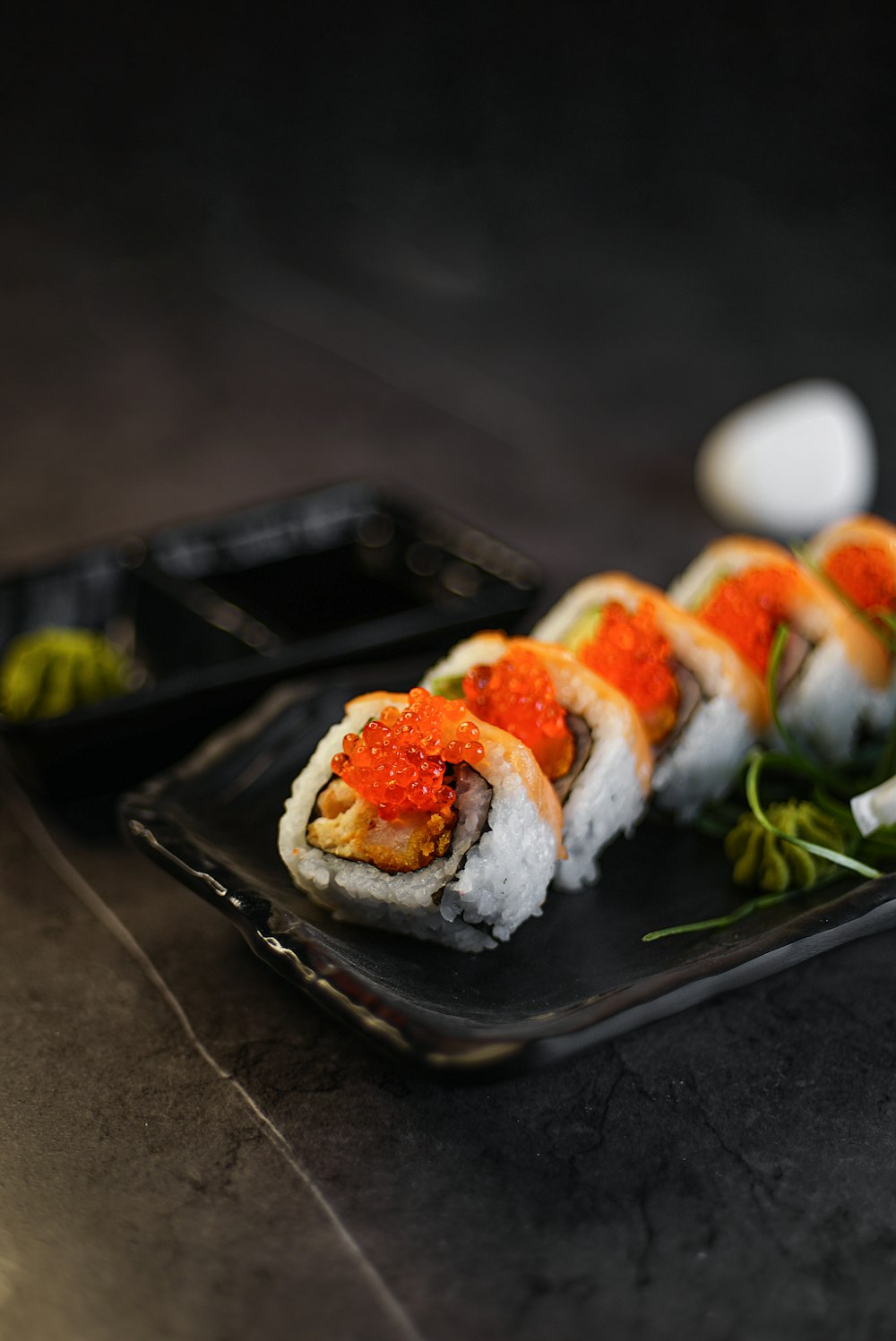 a black plate topped with sushi covered in sauce