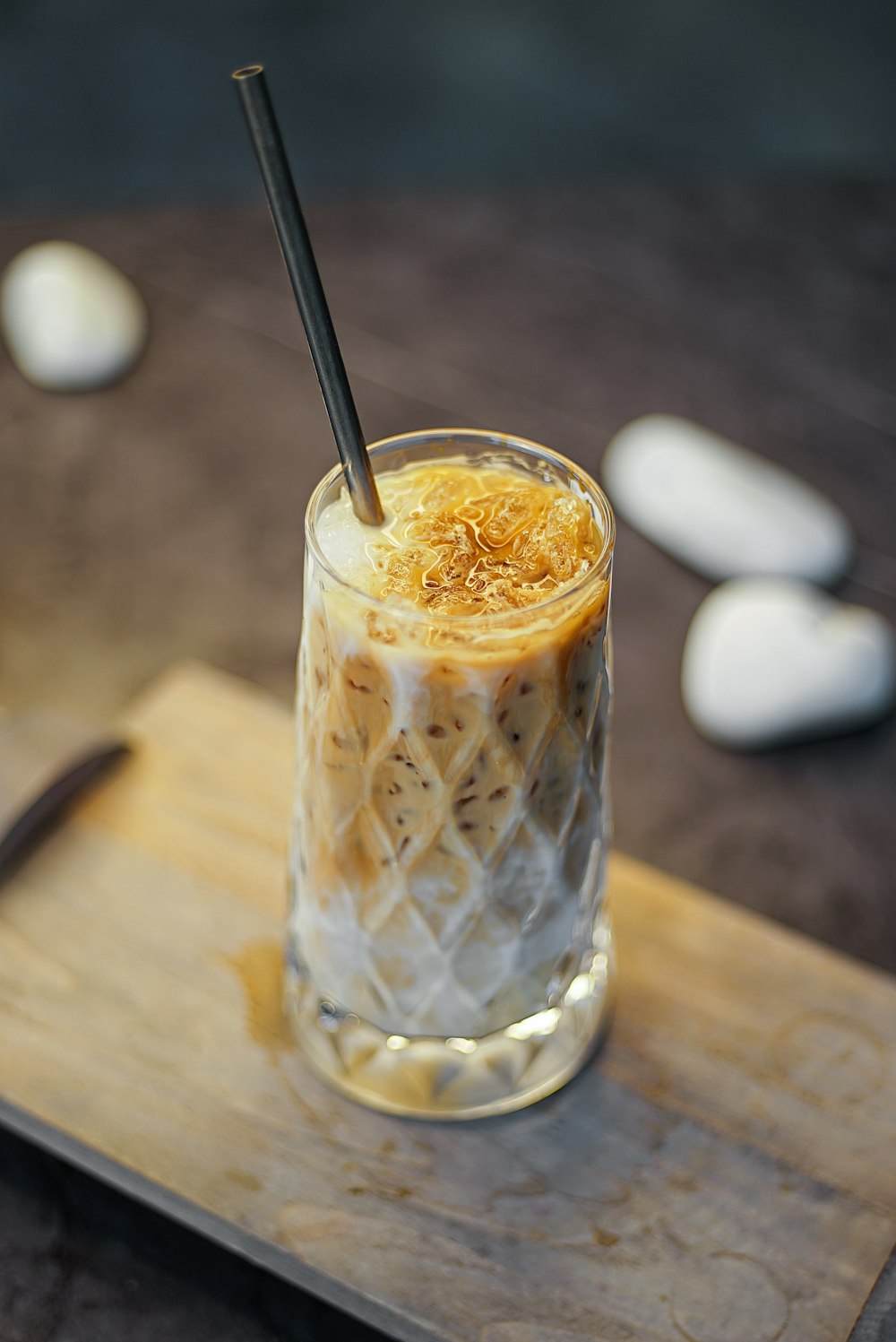 a glass filled with a drink sitting on top of a wooden cutting board