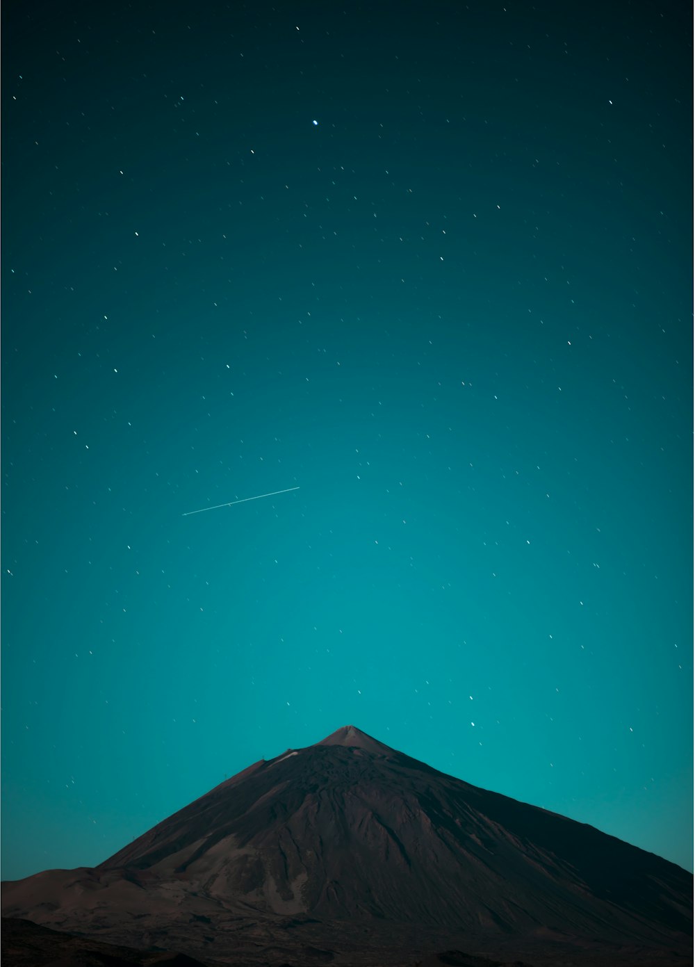 the night sky with stars above a mountain