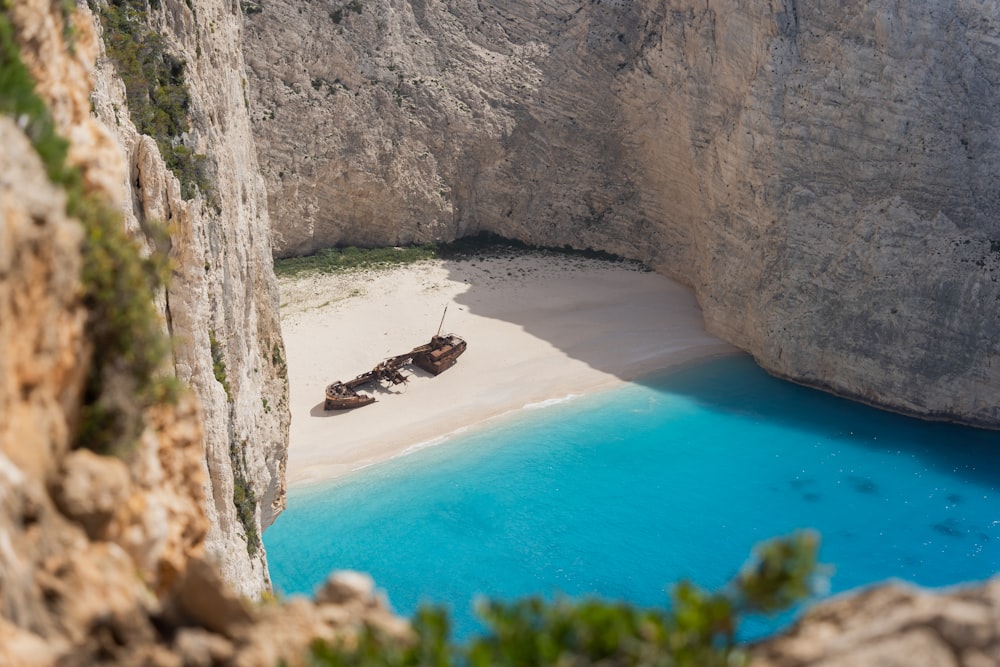 a boat sitting on top of a sandy beach next to a cliff