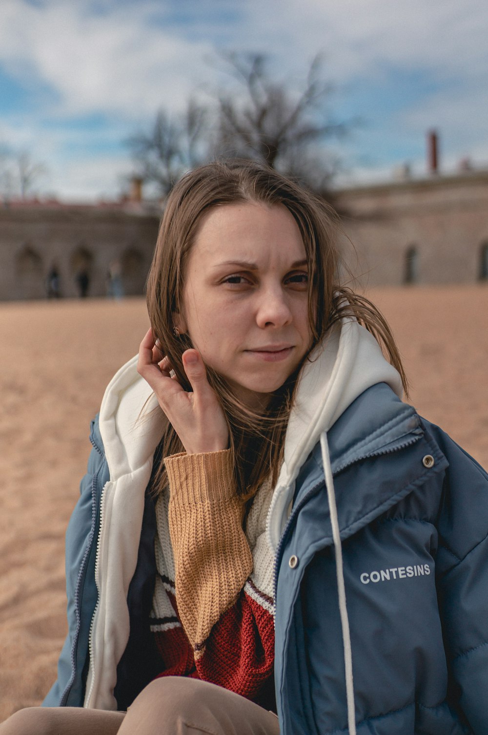 a woman sitting on the beach talking on a cell phone