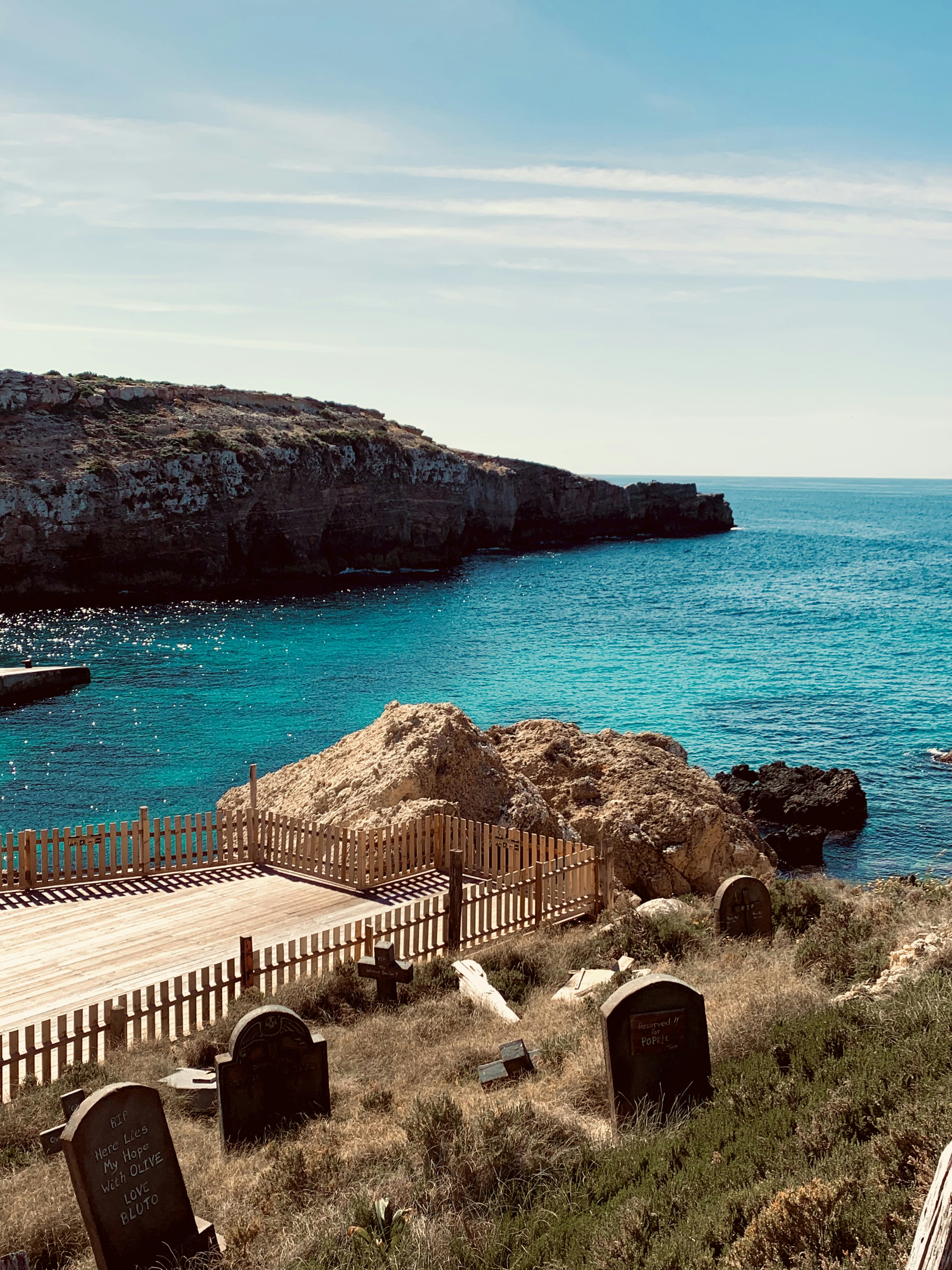 a wooden bench sitting on top of a grass covered hillside next to the ocean